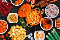 Halloween candy buffet table scene over a black stone background. Assortment of sweet, spooky t ...