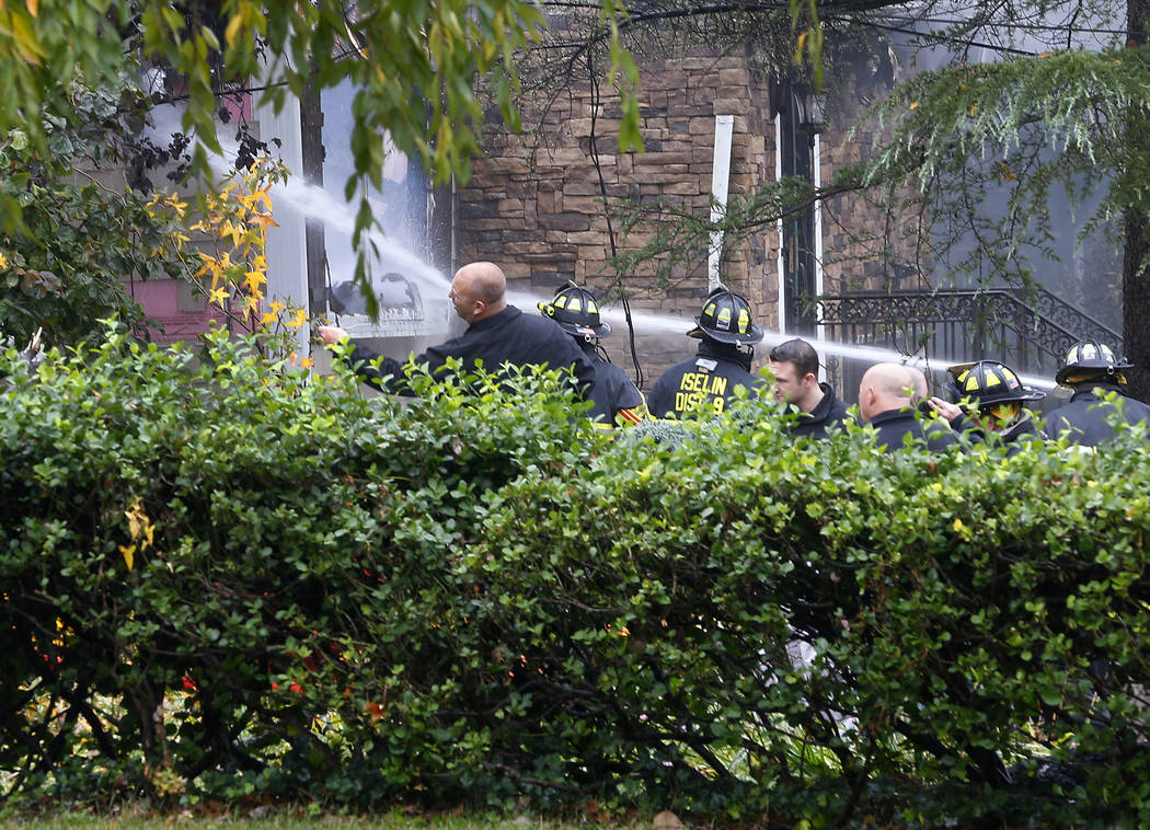 Woodbridge firefighters work to extinguish the scene of a plane crash at a home in Woodbridge, ...