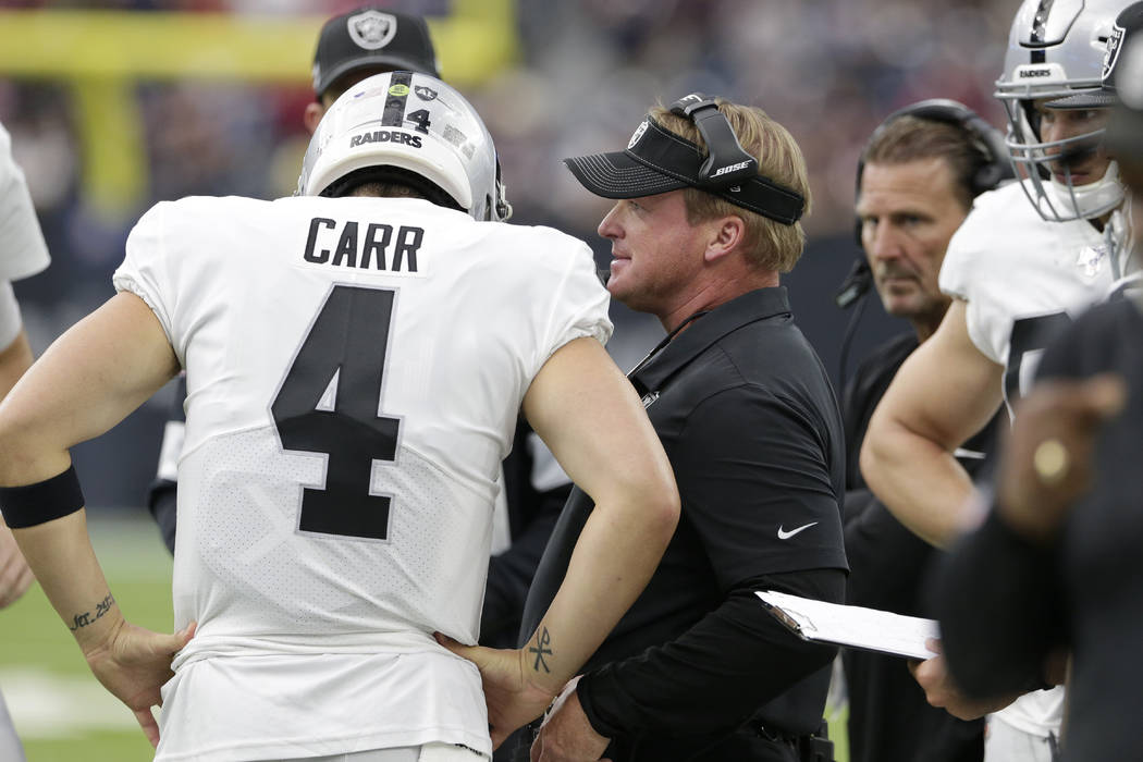 Oakland Raiders head coach Jon Gruden, center, talks with quarterback Derek Carr (4) during the ...