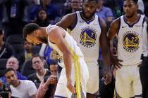 Golden State Warriors' Stephen Curry, left, grimaces as Eric Paschall (7) and Glenn Robinson II ...