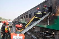 Rescue workers look for survivors following a train damaged by a fire in Liaquatpur, Pakistan, ...