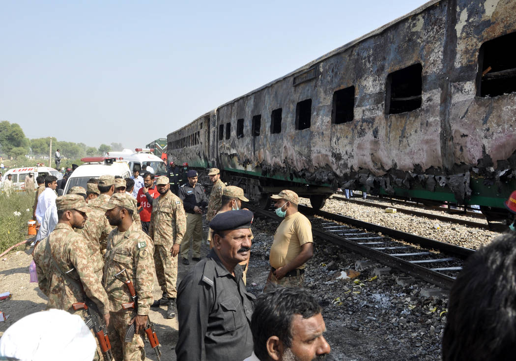 Pakistani soldiers and officials examine a train damaged by a fire in Liaquatpur, Pakistan, Thu ...