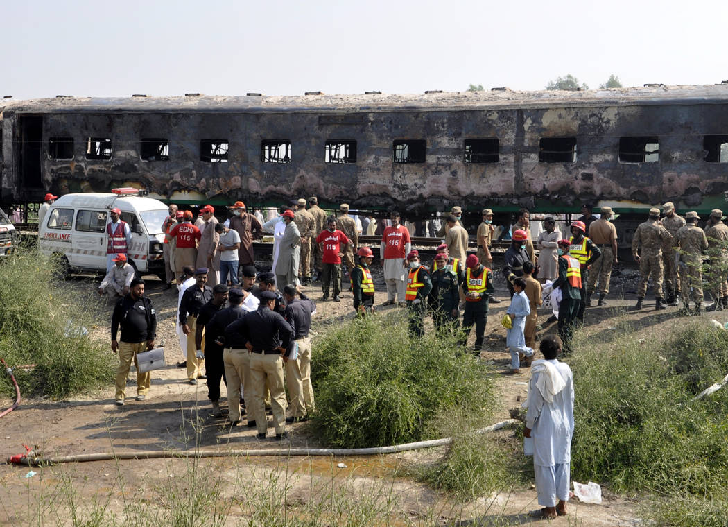 Pakistani soldiers and officials examine a train damaged by a fire in Liaquatpur, Pakistan, Thu ...