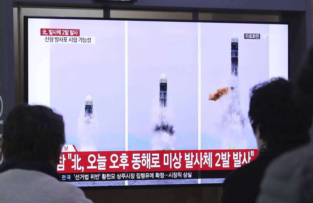 People watch a TV showing file images of North Korea's missile launch during a news program at ...