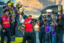 Top Fuel race winner Brittany Force hugs a crew member while carrying her trophy following the ...