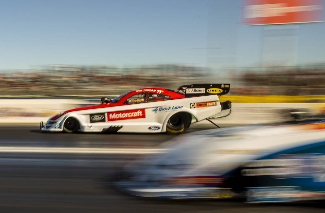 Funny car racer Bob Tasca III, left, takes the lead in the second round during the Dodge NHRA N ...