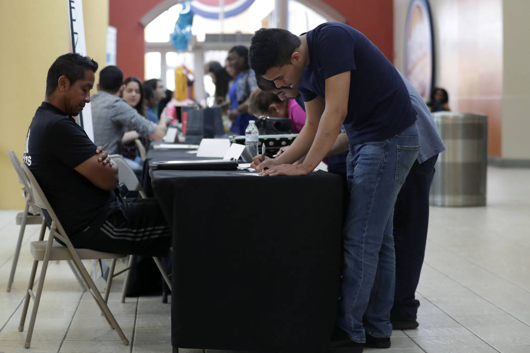 In a Oct. 1, 2019, file photo Billy Ramos, right, fills out a job application with Adidas durin ...