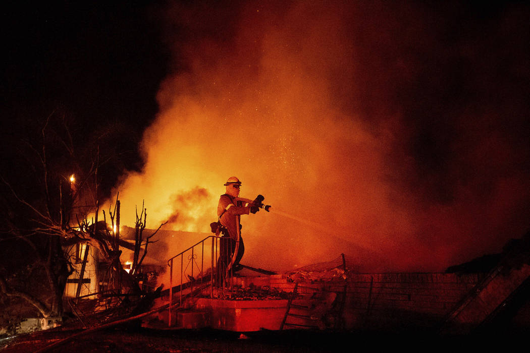 Firefighter Jesse Sparks mops up at a destroyed home as the Hillside Fire burns in San Bernardi ...