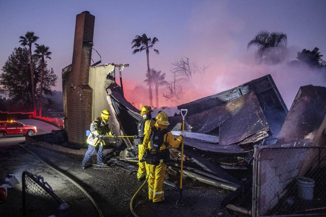 Firefighters mop up at a leveled home as the Hillside Fire burns in San Bernardino, Calif., on ...