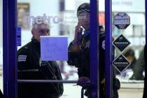 A police supervisor and officer stand inside a cell phone store in the 3700 block of West 26th ...