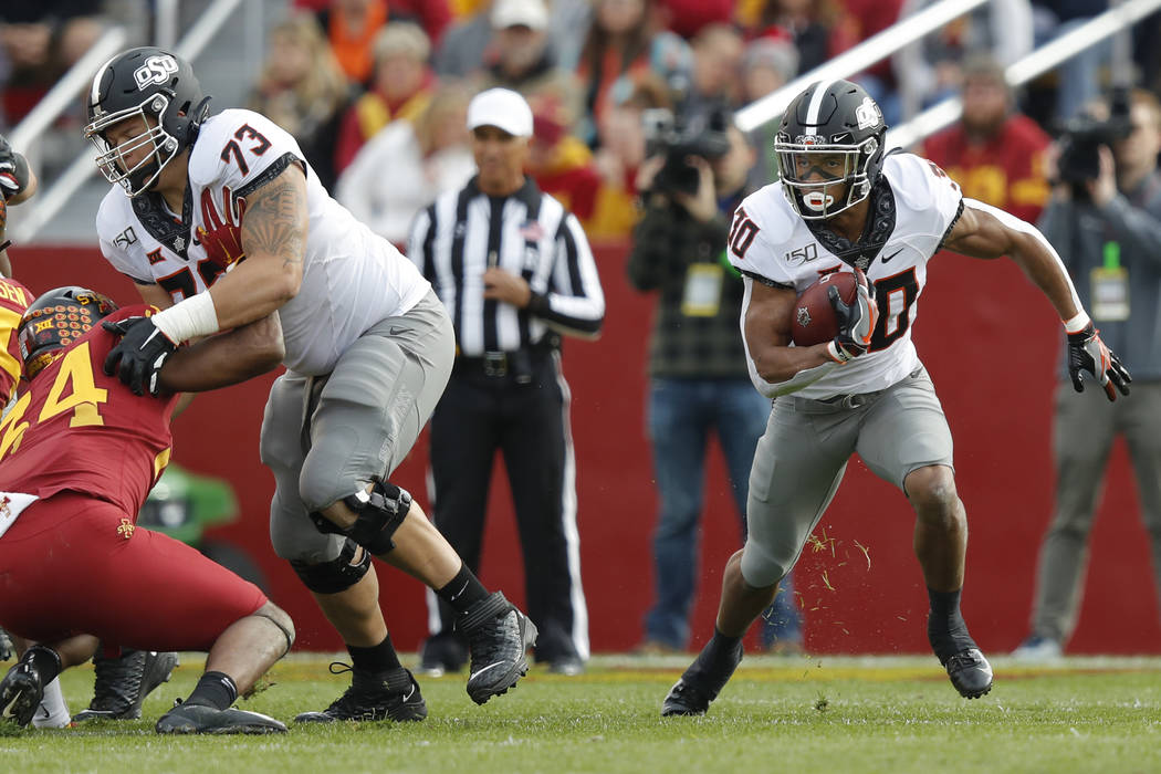 Oklahoma State running back Chuba Hubbard, right, runs the ball during the first half of an NCA ...