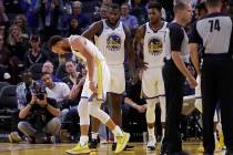 Golden State Warriors' Stephen Curry, left, grimaces after Phoenix Suns' Aron Baynes fell onto ...