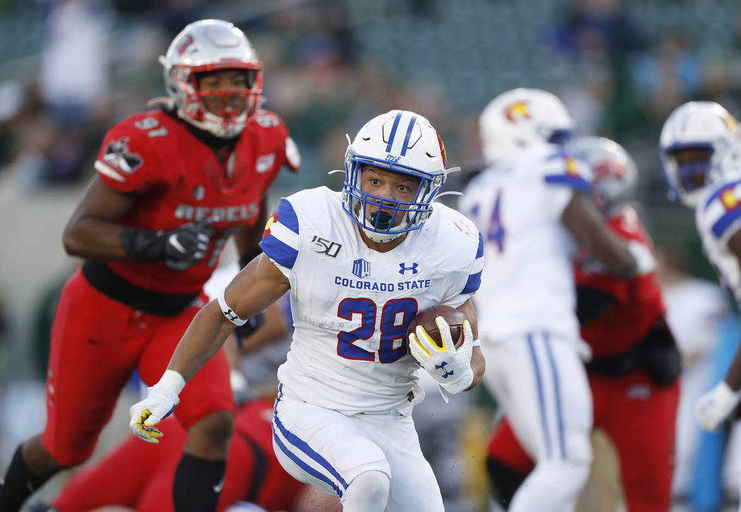 Colorado State running back Christian Hunter, front, runs for a long gain with UNLV defensive l ...