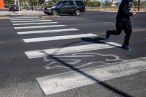 A pedestrian crosses chalk outlines freshly painted by the Las Vegas Fire Department at the int ...