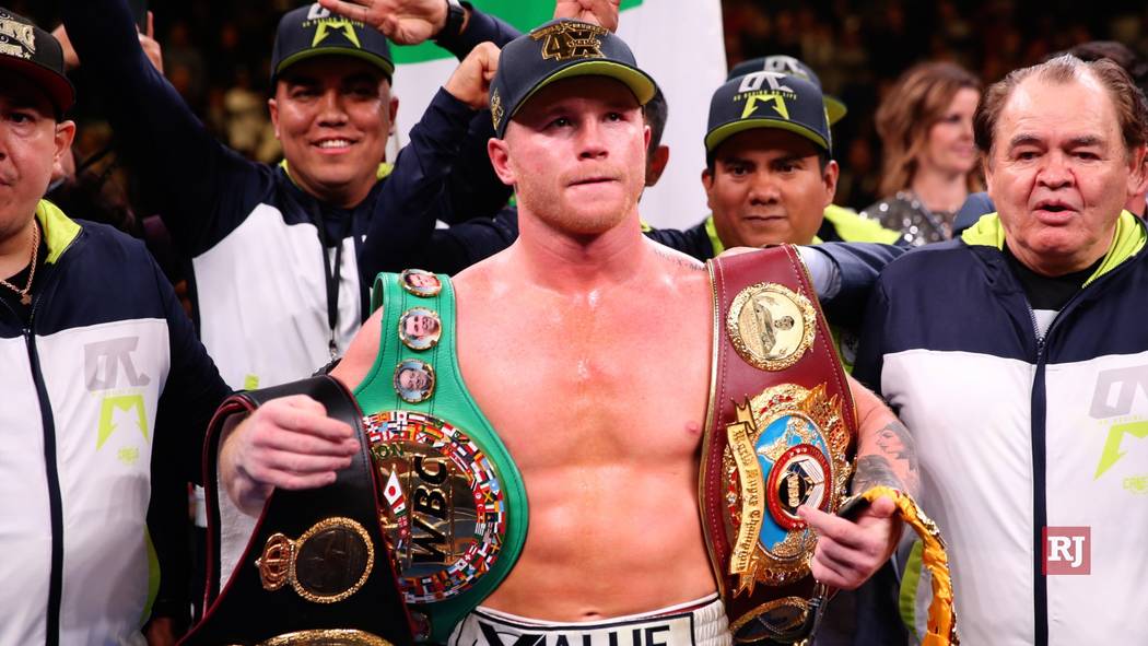 Saul “Canelo” Alvarez, right, holds his belts after winning at the MGM Grand Garden Arena i ...