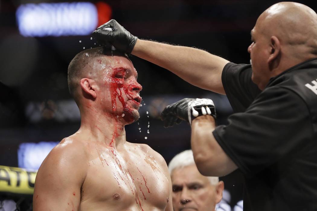 A trainer helps Nate Diaz after the first round of a welterweight mixed martial arts bout again ...