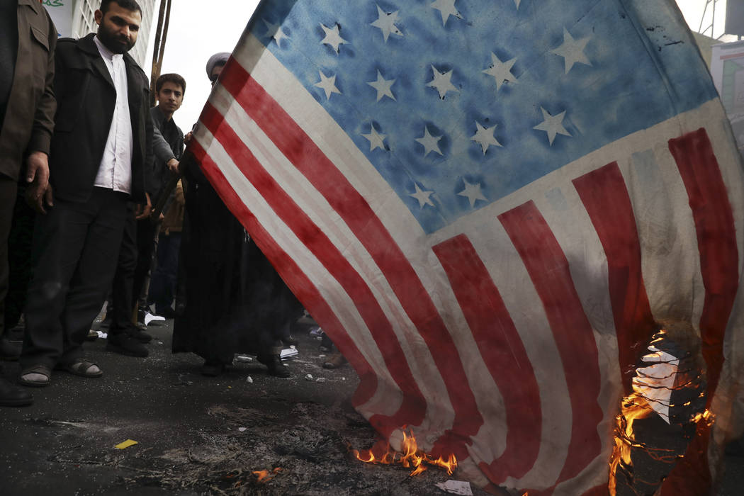 Demonstrators set fire to a rendition of the U.S. flag during a rally in front of the former U. ...