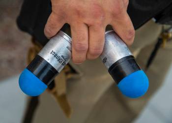 A Metropolitan Police Department officer holds two rounds from a 40mm "Launcher," a new less th ...