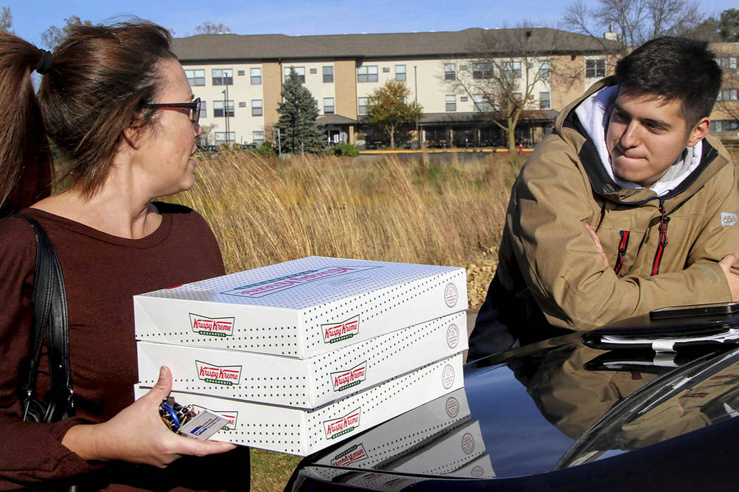 In this Saturday, Oct. 26, 2019 photo, Catherine Newton, left, buys three boxes of Krispy Kreme ...