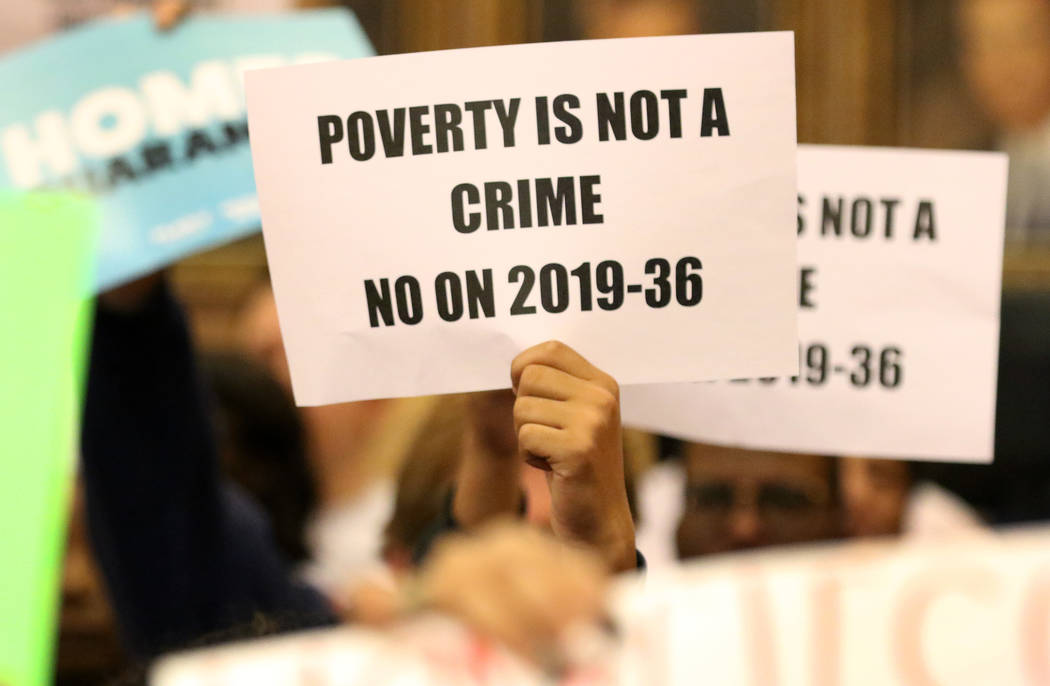 Protesters hold signs inside council chambers during a protest against the city council's contr ...