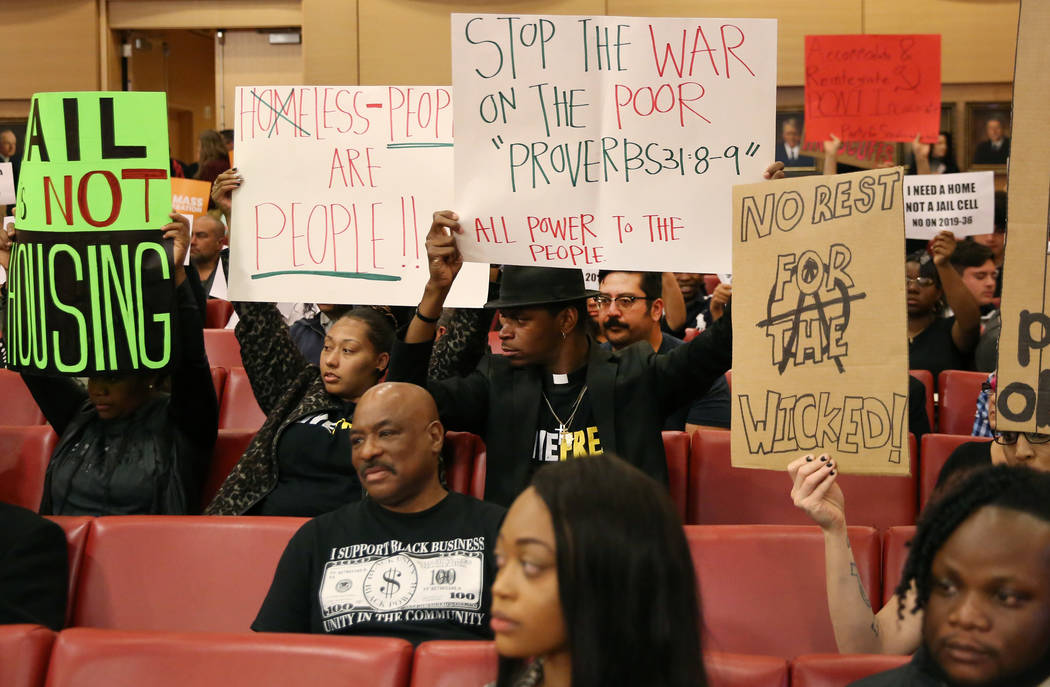 Protesters hold signs inside council chambers during a protest against the city council's contr ...