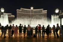 People watch the water fountain show outside the Bellagio hotel and casino on the Strip in Las ...