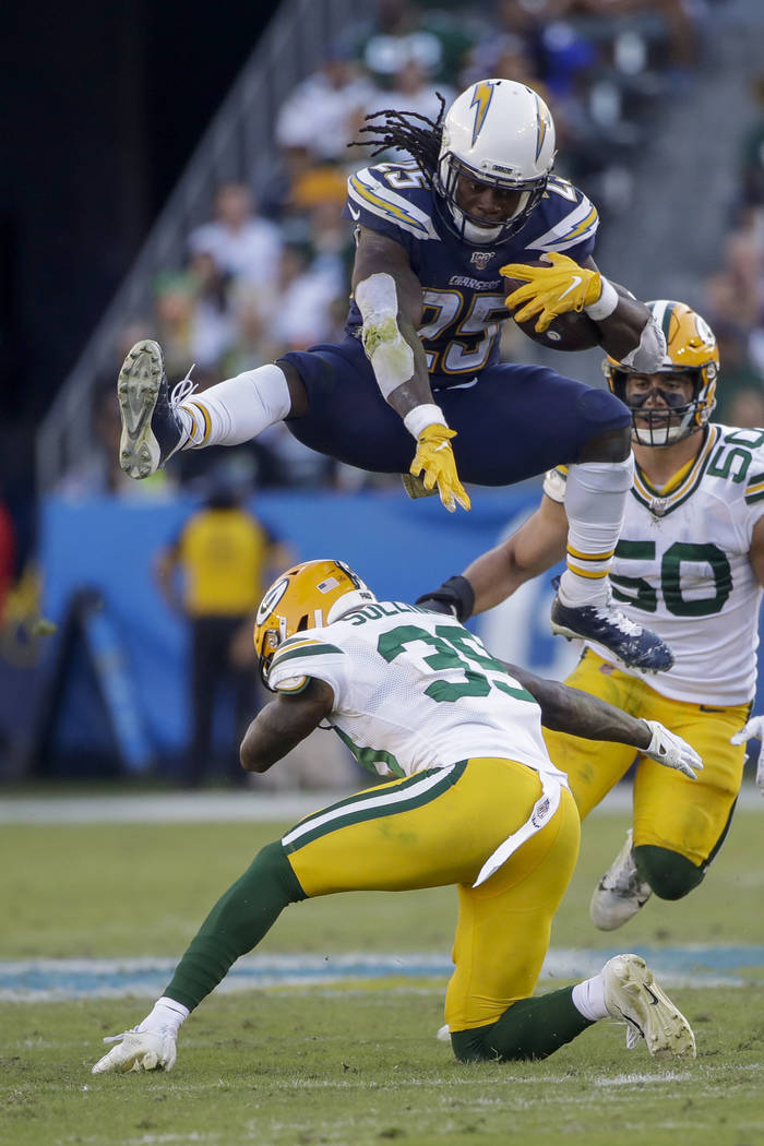 Los Angeles Chargers running back Melvin Gordon jumps over Green Bay Packers defensive back Cha ...