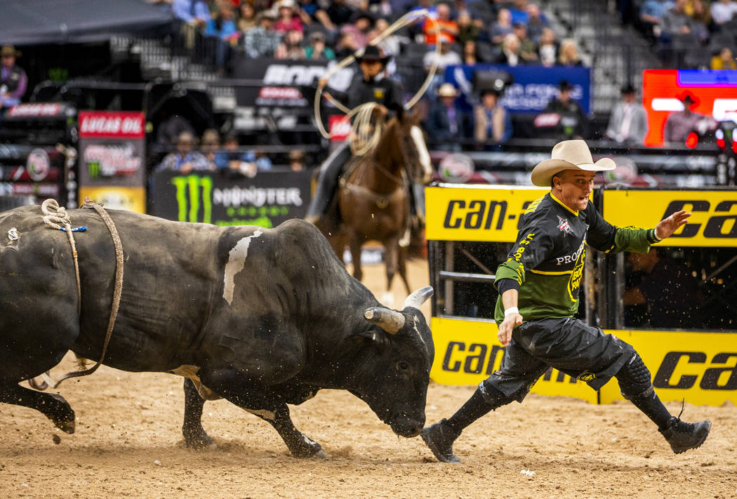 Bullfighter Frank runs to escape the horns of a bull during the PBR World Finals at T-Mobile Ar ...