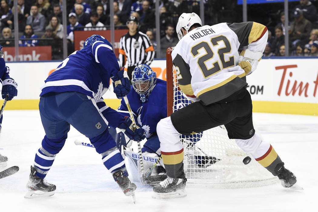 Vegas Golden Knights defenseman Nick Holden (22) tries to jam the puck past Toronto Maple Leafs ...