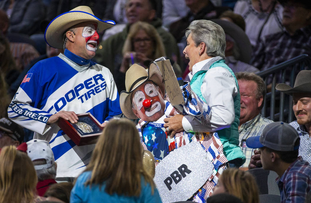 Rodeo clown Flint Rasmussen trades a fan a belt buckle for a jacket during the PBR World Finals ...