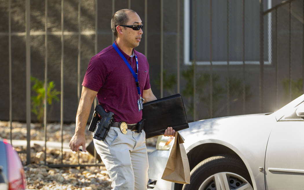 An officer departs the scene carrying a brown bag during an officer-involved shooting at The Eq ...