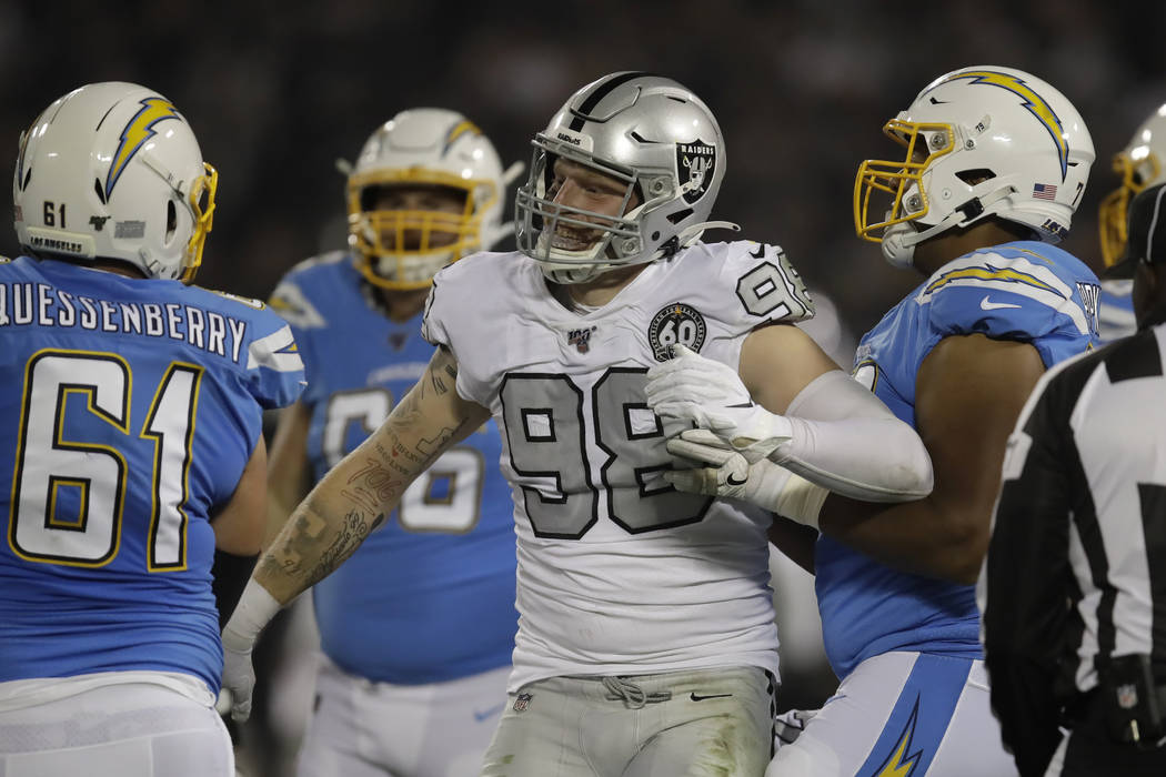 Oakland Raiders defensive end Maxx Crosby (98) reacts next to Los Angeles Chargers center Scott ...