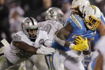 Los Angeles Chargers running back Melvin Gordon, right, carries as Oakland Raiders defensive en ...