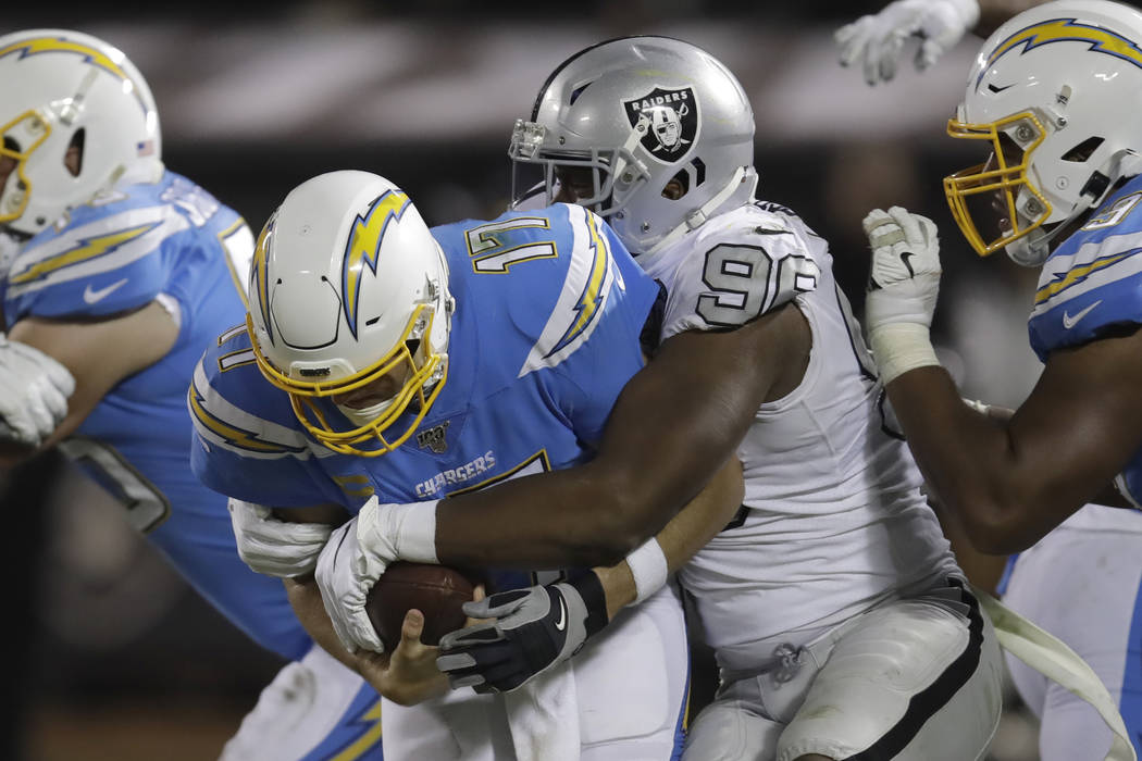 Los Angeles Chargers quarterback Philip Rivers (17) is tackled by Oakland Raiders defensive end ...
