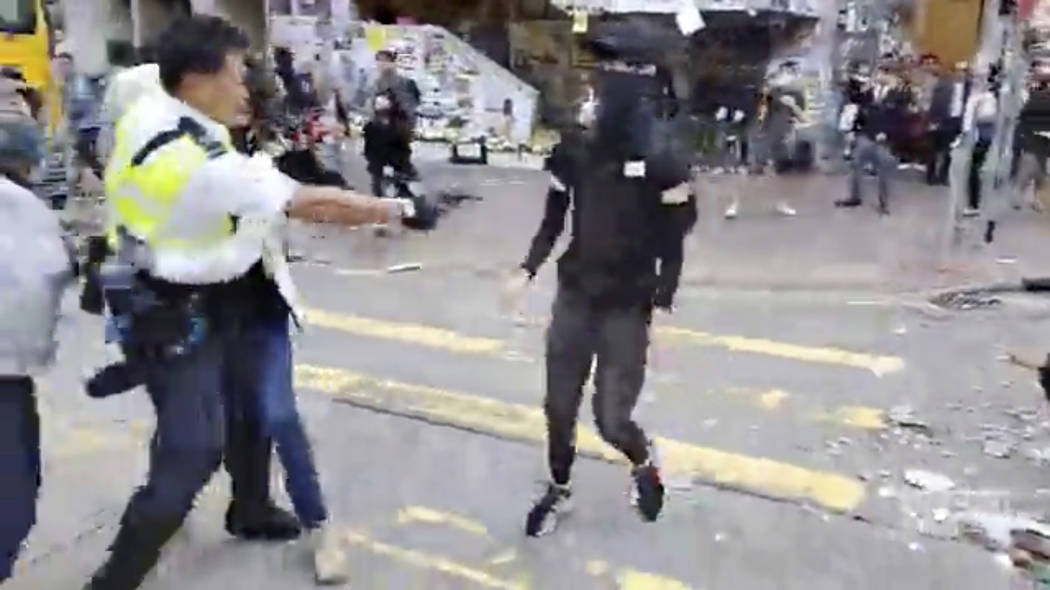 In this image made from video, a police officer, left, prepares to shoot a protester, center, i ...