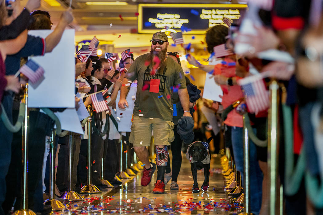 Wounded veteran Christopher Miller and his dog Zulu are celebrated by employees as makes their ...