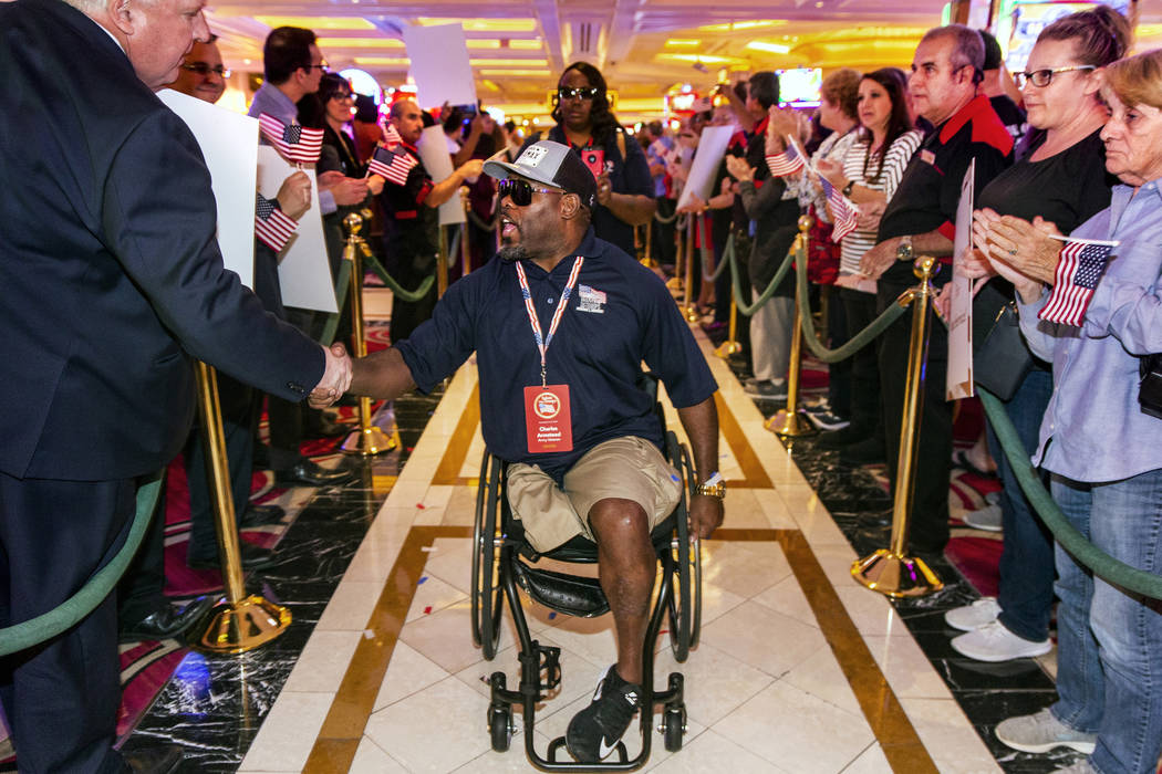 Wounded veteran Charles Armstead, center, is greeted and applauded by employees as he makes his ...