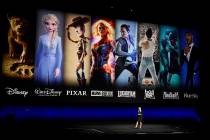 Characters from Disney and Fox movies are displayed behind Cathleen Taff of Walt Disney Studios ...