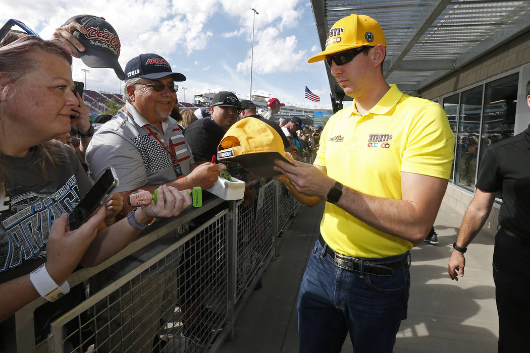 Driver Kyle Busch, right, gives autographs to fans prior to a NASCAR Cup Series auto race at IS ...