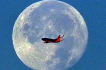 A Southwest Airlines plane flies in front of a full moon in the early morning of Wednesday, Nov ...