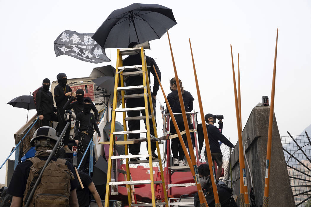 Protesters look out from a raised platform on a barricaded bridge which leads into the Chinese ...