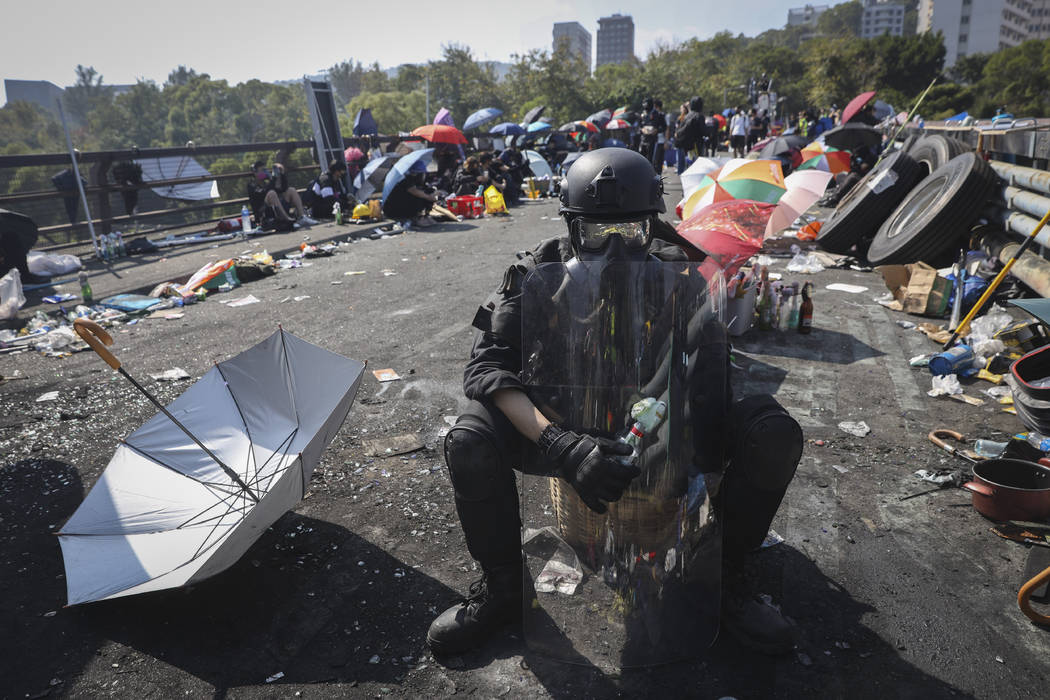 A pro-democracy protester with protection gears holds a bottle of molotov cocktail on a bridge ...