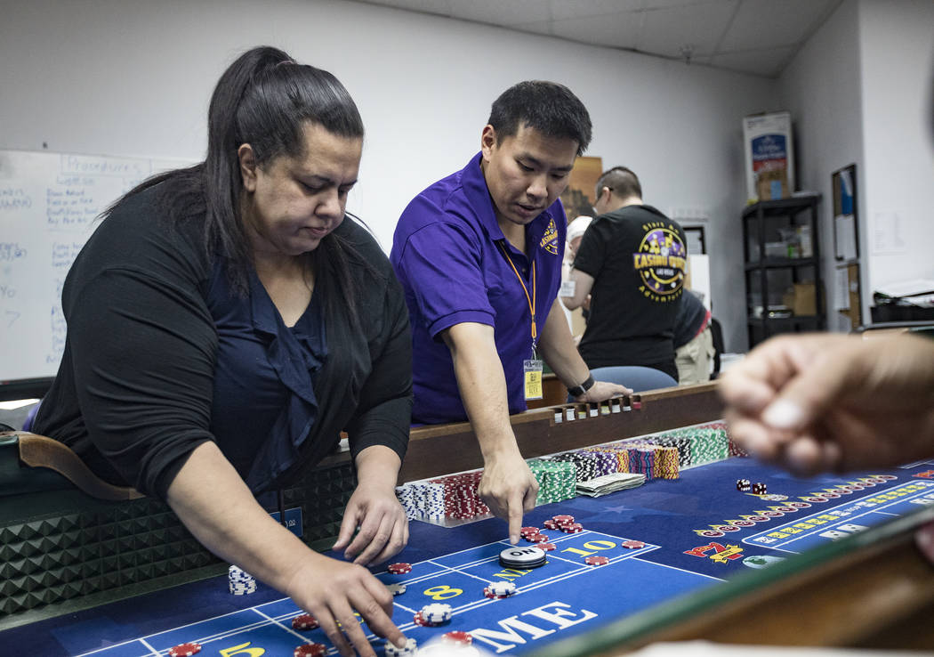 Michelle Robson, left, gets help from Alex Kim, executive director of Casino Education Group, a ...