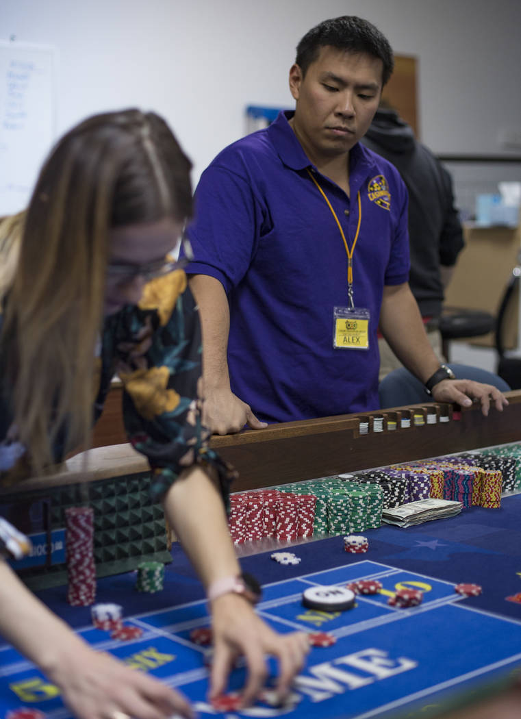 Alex Kim, executive director of Casino Education Group, center, helps Fred Chubay, right, watch ...