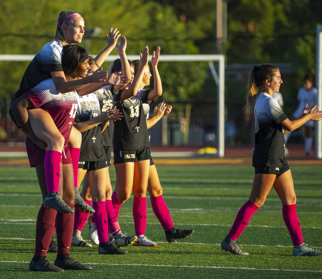 Faith Lutheran's goal keeper Jordan Brown (47, left) carries teammate Kylie Harris (30) as they ...