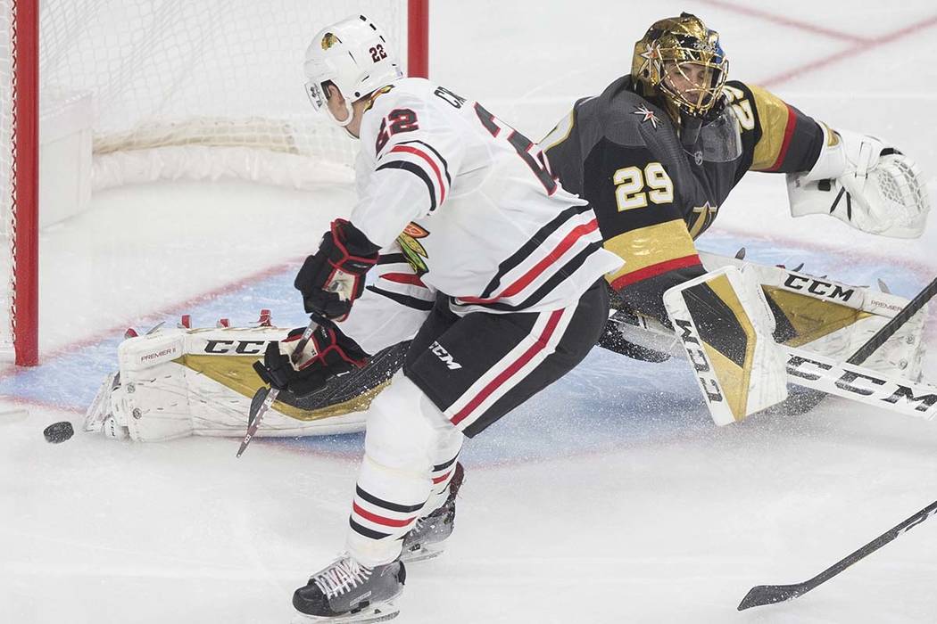 Chicago Blackhawks center Ryan Carpenter (22) watches a shot from teammate Kirby Dach (77) (out ...