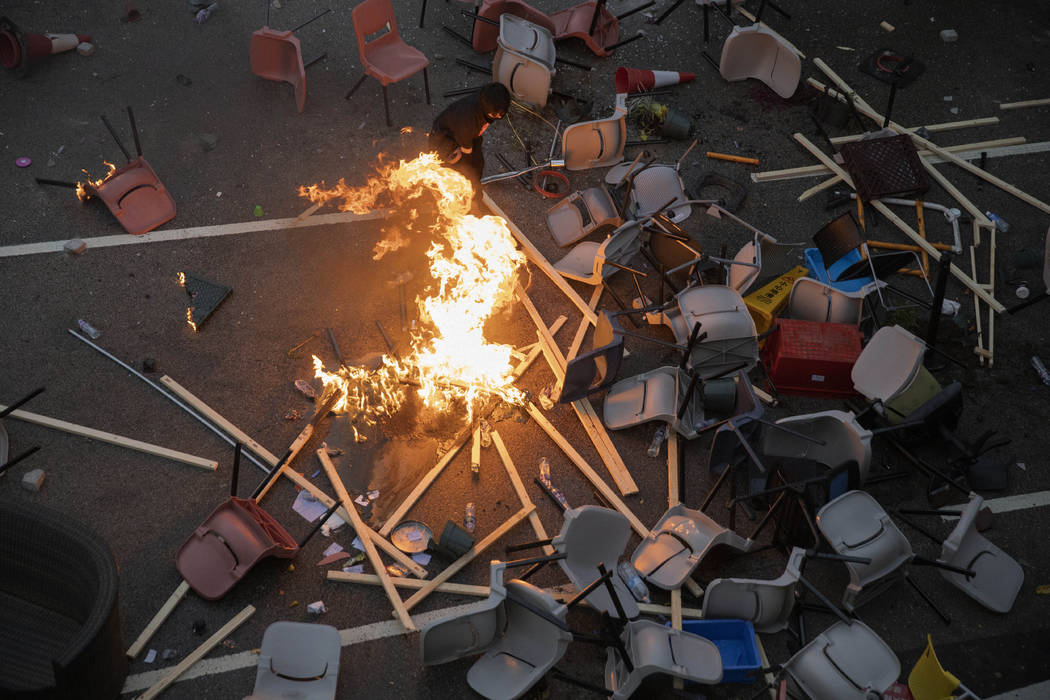 A protester tries to pour water on a fire burning amid debris placed to block a road leading to ...