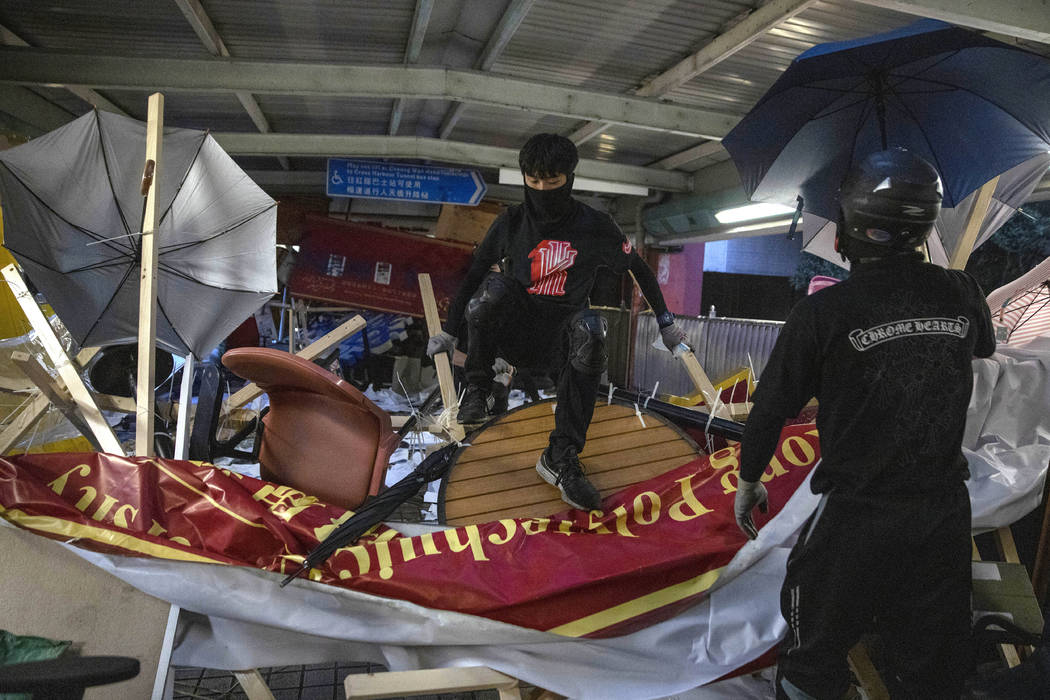Protesters climb over a barricade on an overhead bridge near the Cross-Harbour Tunnel in Hong K ...