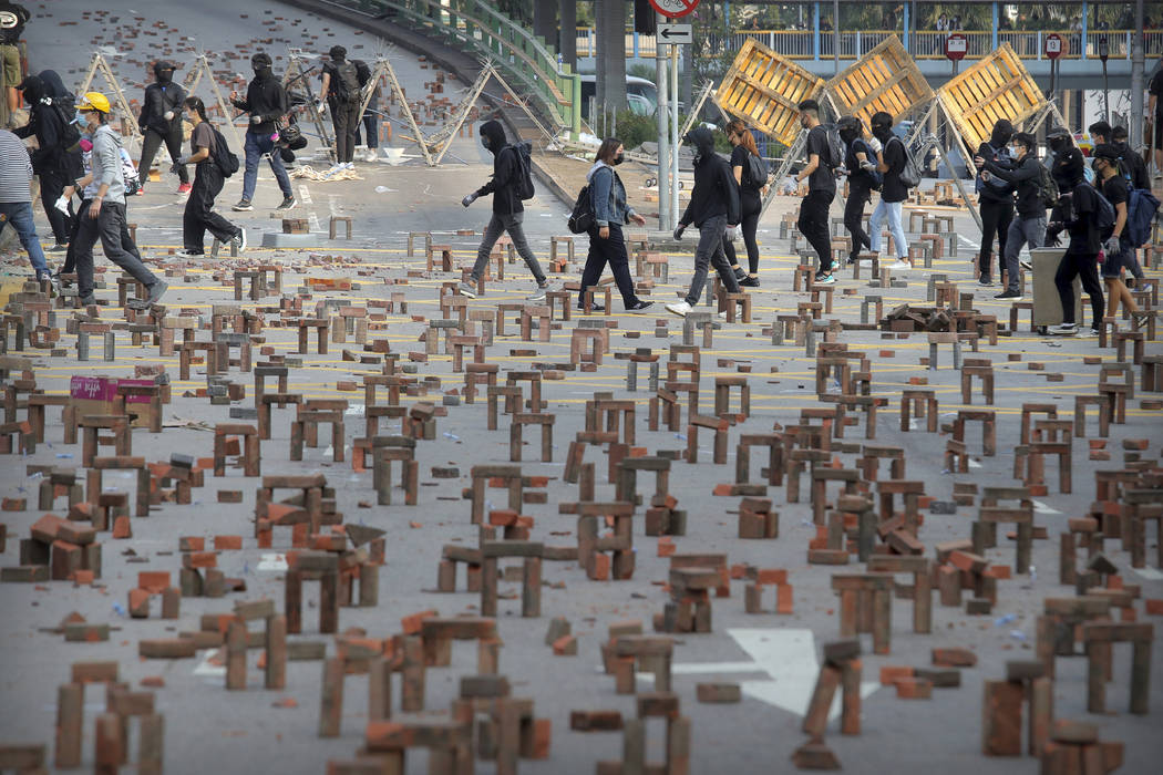 Protesters walk past barricades of bricks on a road near the Hong Kong Polytechnic University i ...