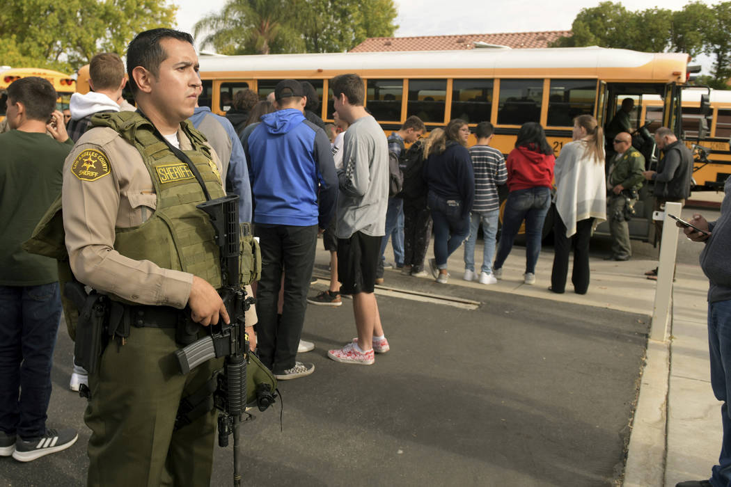 Students evacuate their campus after a gunman opened fire at Saugus High School on Thursday, No ...